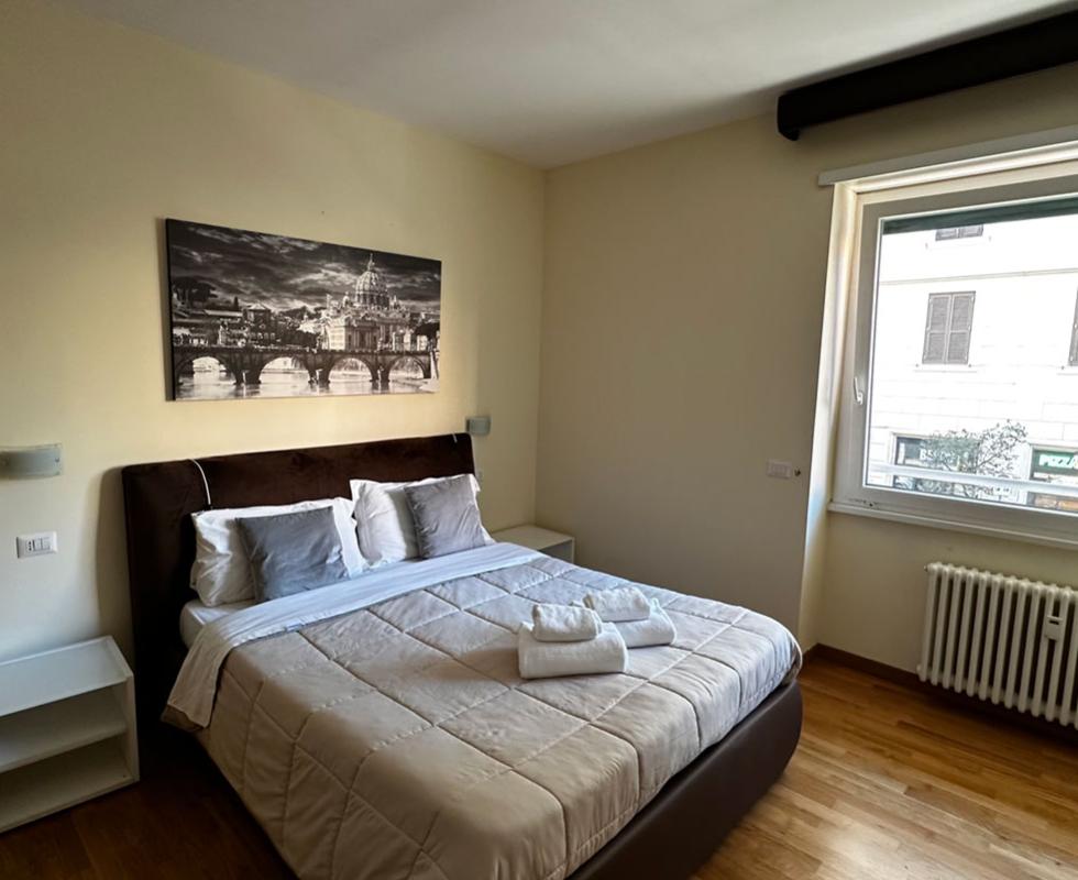 Camera moderna con letto matrimoniale, finestra ampia e quadro in bianco e nero.