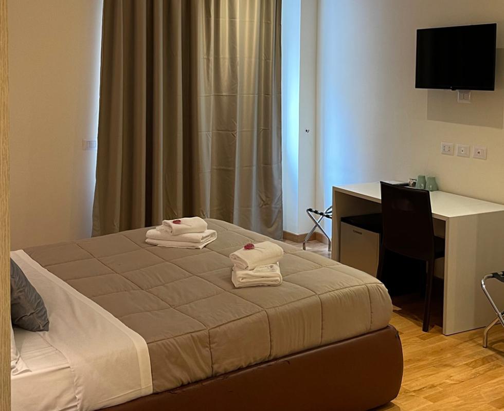 Camera d'albergo accogliente con letto matrimoniale, scrivania e TV a parete.