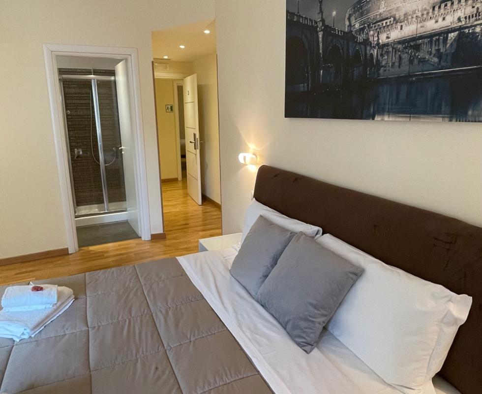 Camera moderna con letto matrimoniale, bagno privato e decorazione murale.